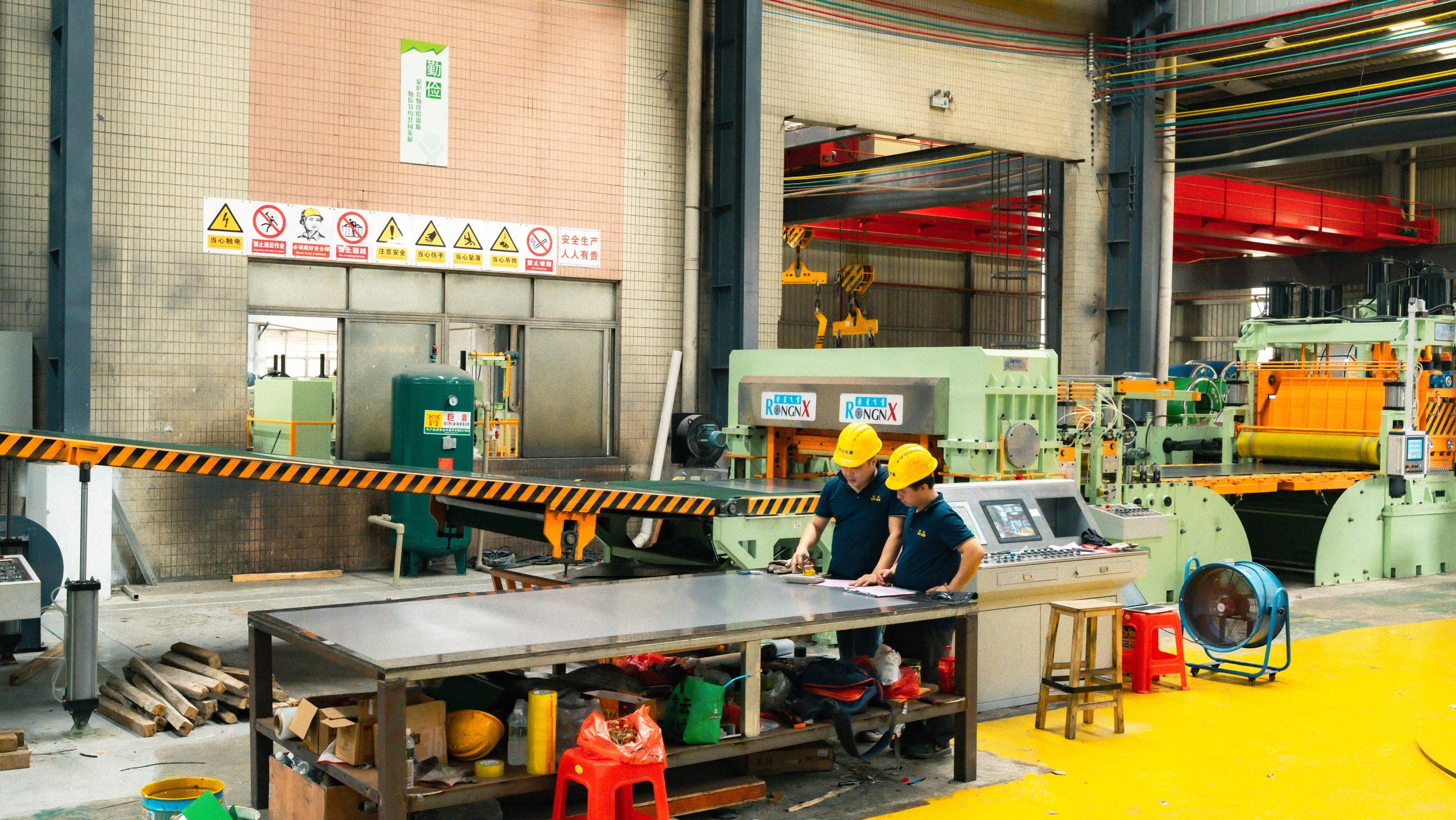 RONGXING engineers inspecting sheet output from a 1650mm Flying Shear line
